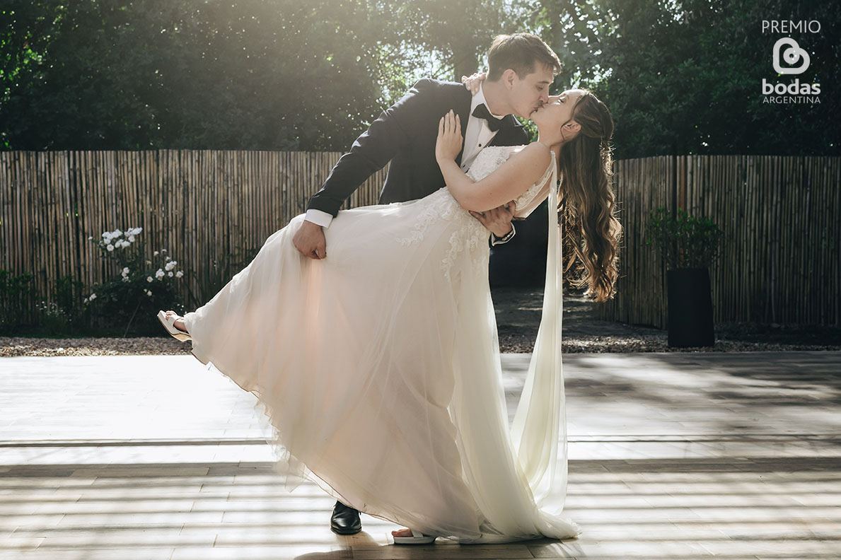 Novios besándose en el jardín con cerco de bambú