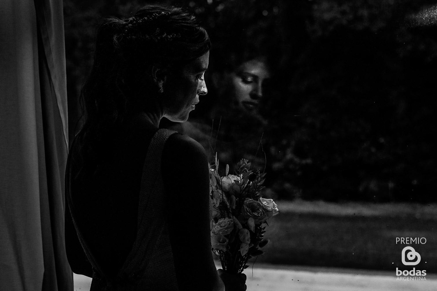 Silueta de la novia mirando por la ventana con su ramo