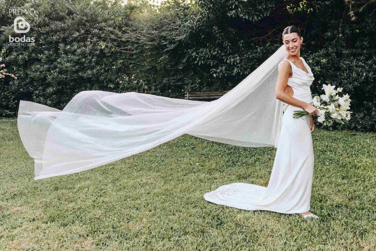 Novia con velo flameando al viento en el jardín